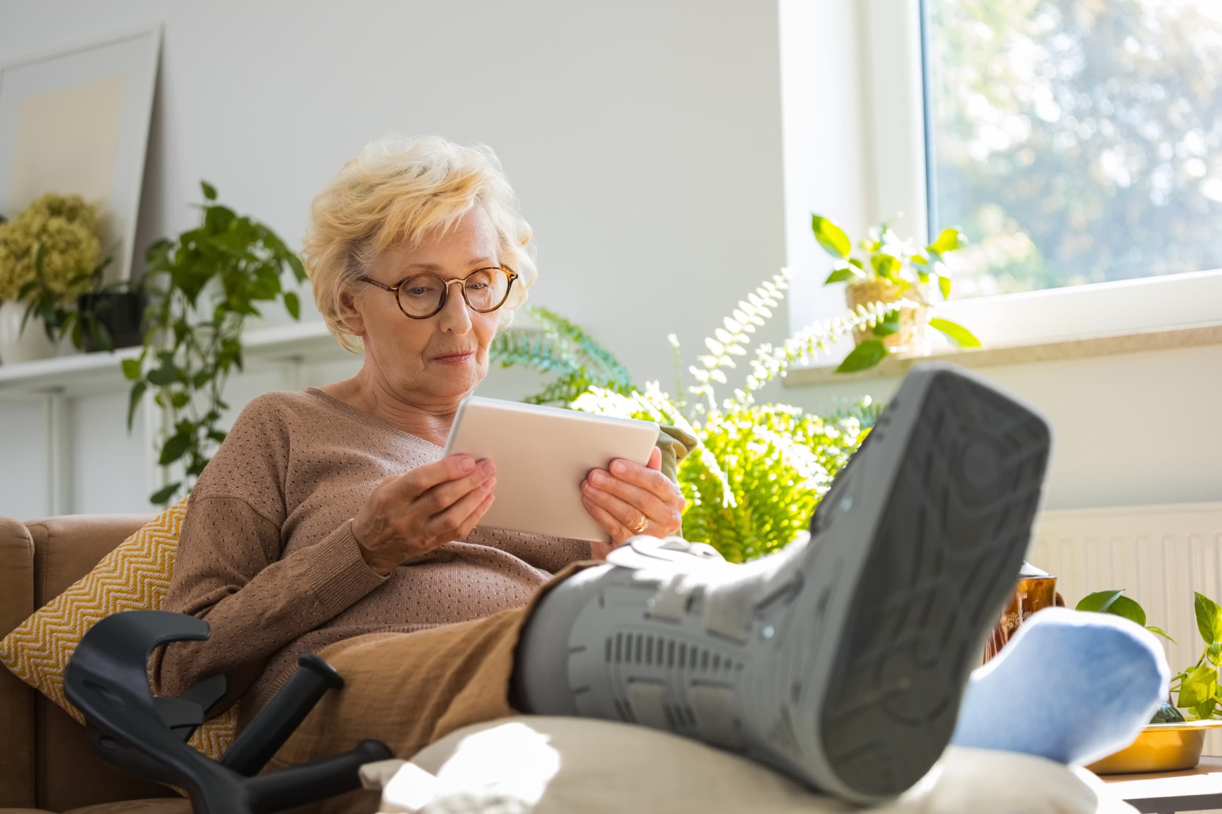 Older woman recovering at home with a walking boot after a low-impact fracture