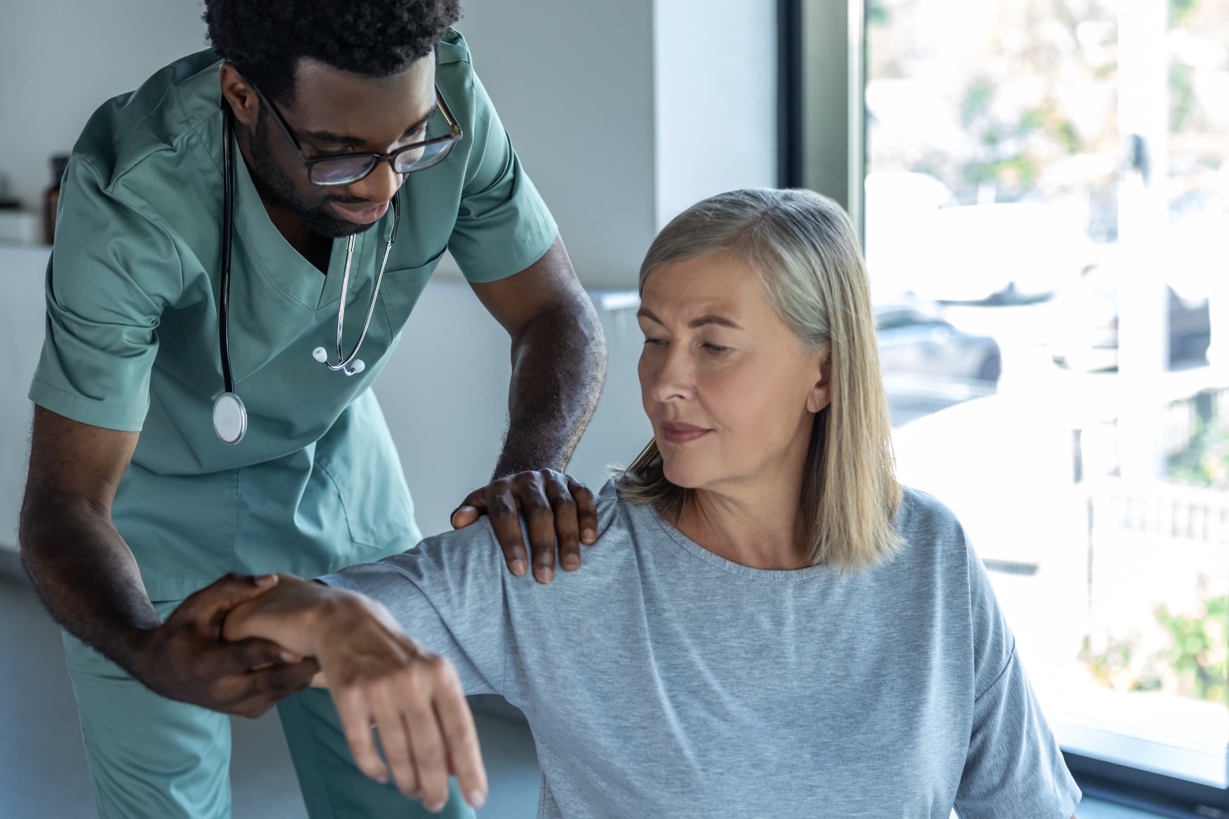 Clinician assessing the range of motion of an older woman's shoulder
